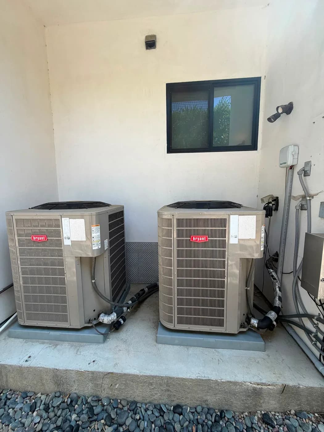 Two Bryant outdoor AC condenser units installed side by side against a stucco wall