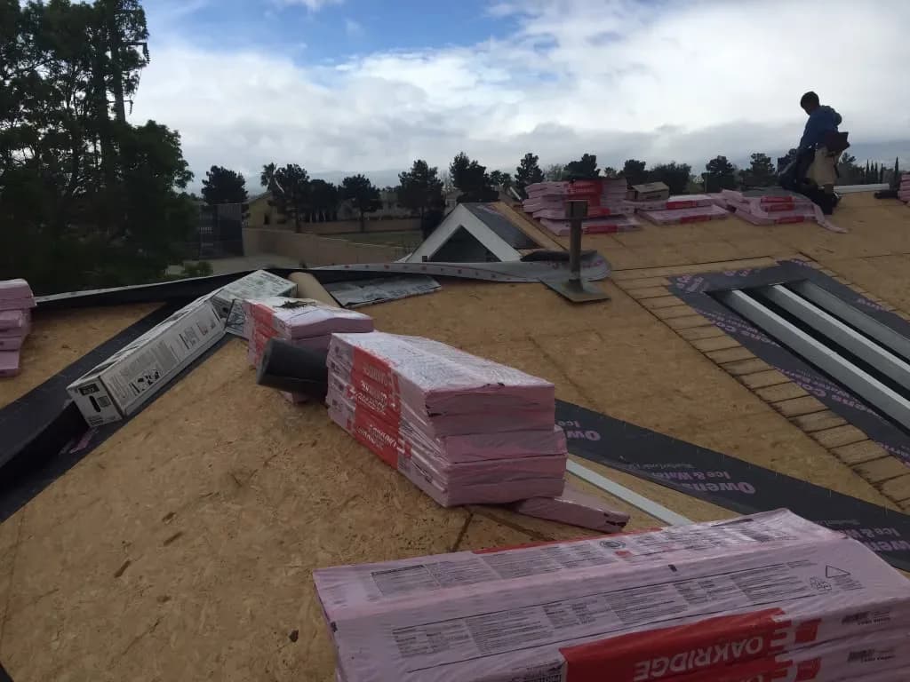 Roofing materials and flashing pieces staged on a deck during reroofing