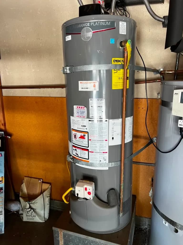 Close-up of gas water heater tank connections and energy rating label