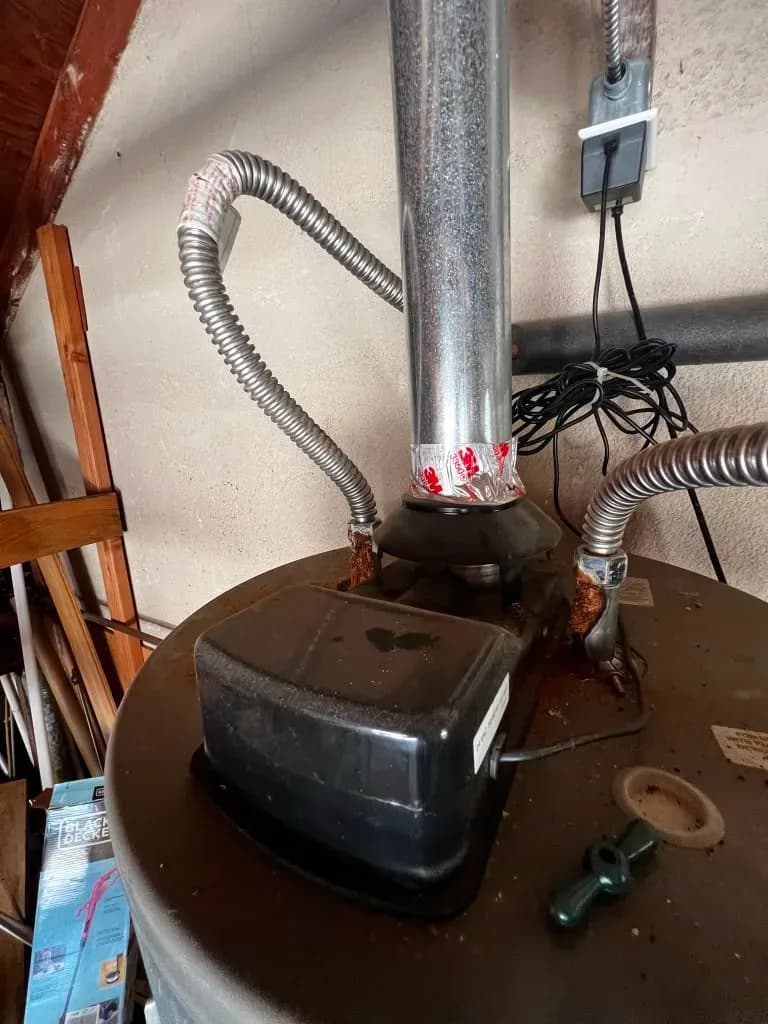 Close-up of water heater flue vent and gas line connections